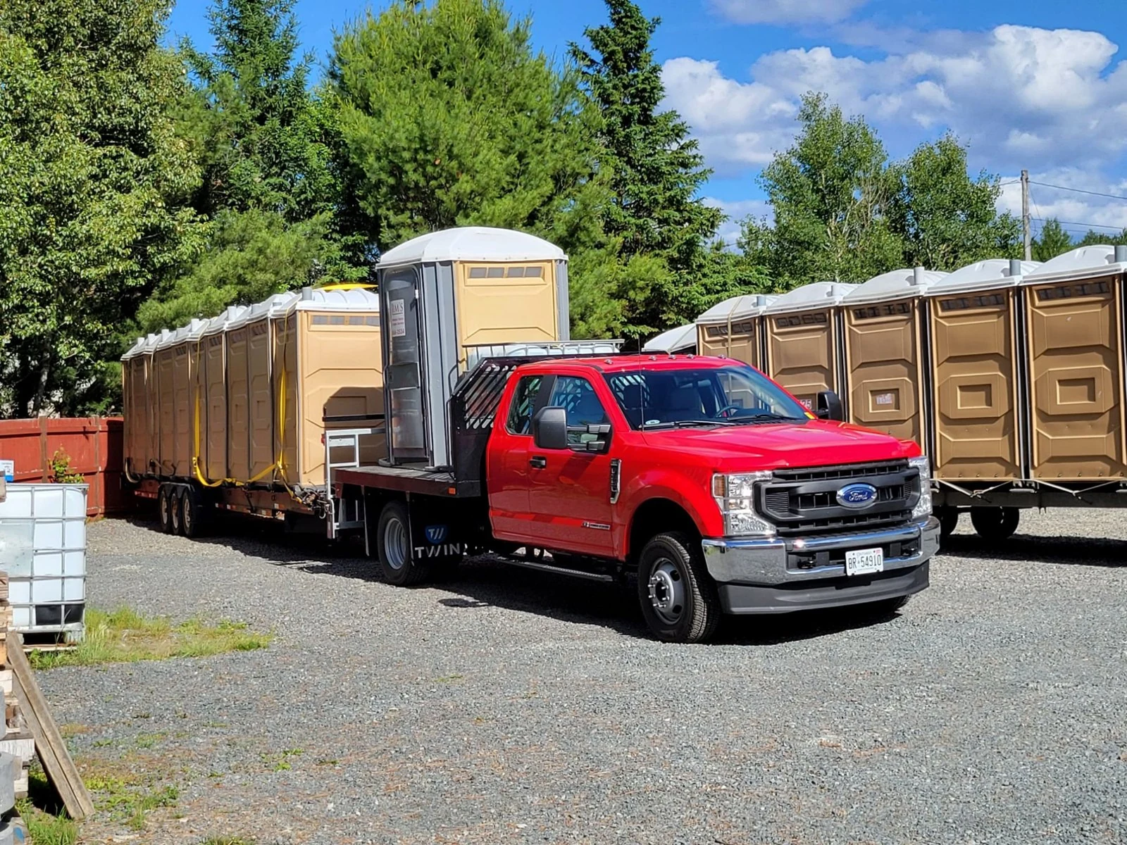 Jim’s Portable Toilets & Septic Service: red truck hauling portable toilets